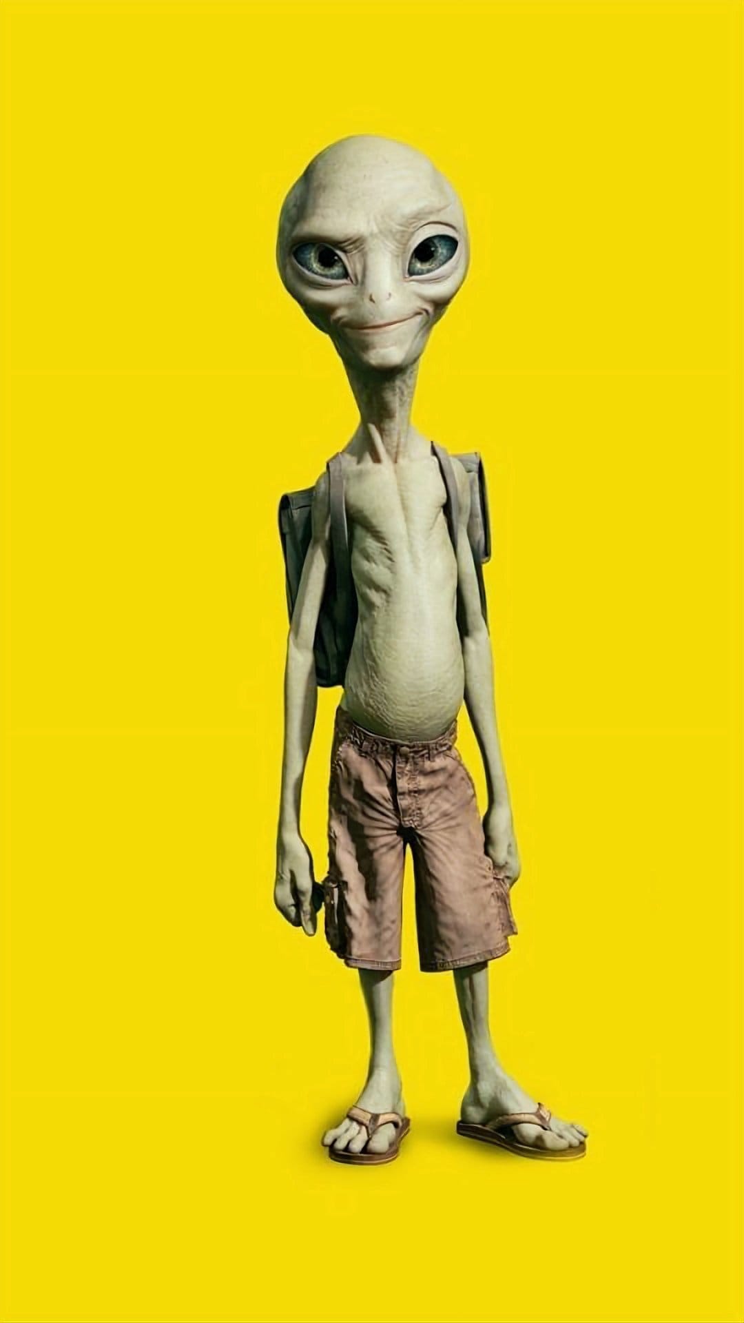 Slender green alien with large black eyes wears brown cargo shorts and a backpack against a solid yellow backdrop.