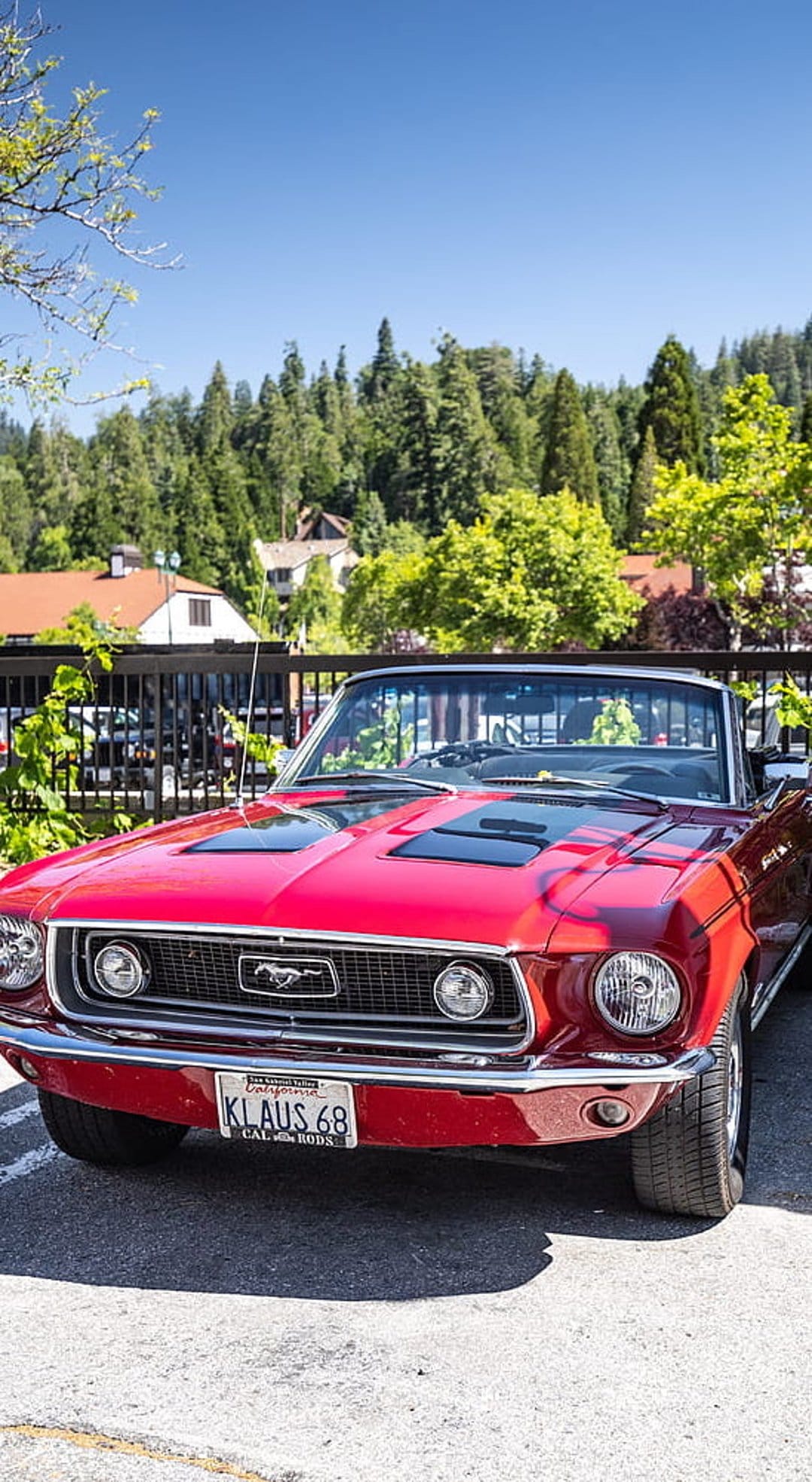 Red 1968 Ford Mustang convertible with chrome grille and California license plate parked on a sunny day.