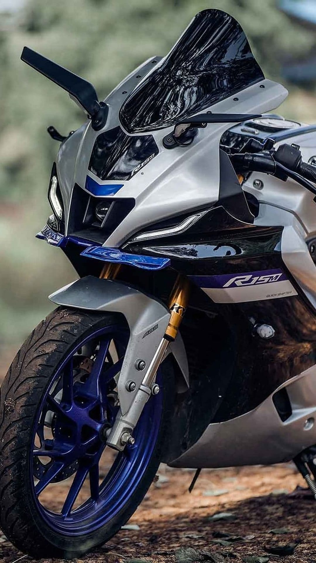 Yamaha R15 sport motorcycle features sleek silver fairings, LED headlights, and vibrant blue alloy wheels.