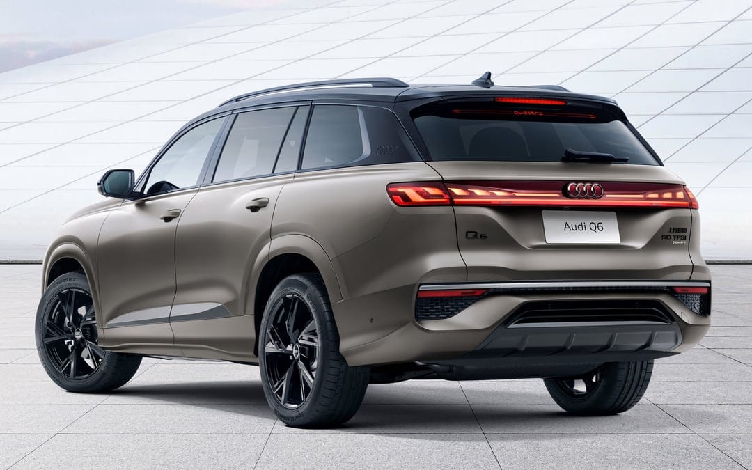Matte bronze Audi Q6 SUV showing rear LED lights and black wheels against a white architectural background.