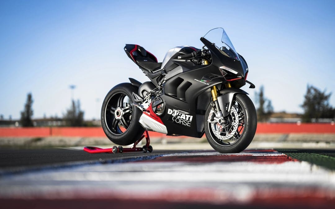 Matte black Ducati Panigale V4 SP2 motorcycle on a racetrack under a clear sky with gold front forks.