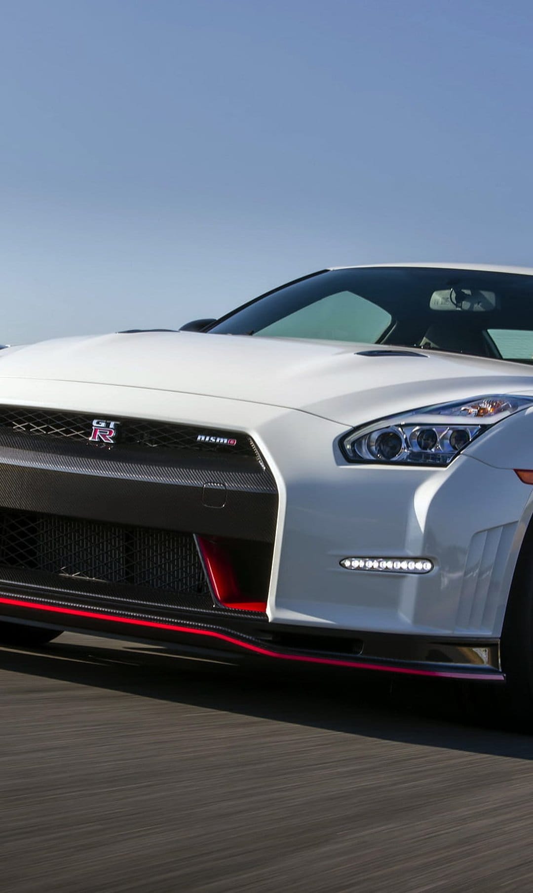 Nissan GT-R Nismo with a white exterior, red trim on carbon fiber aero, and a honeycomb black front grille.