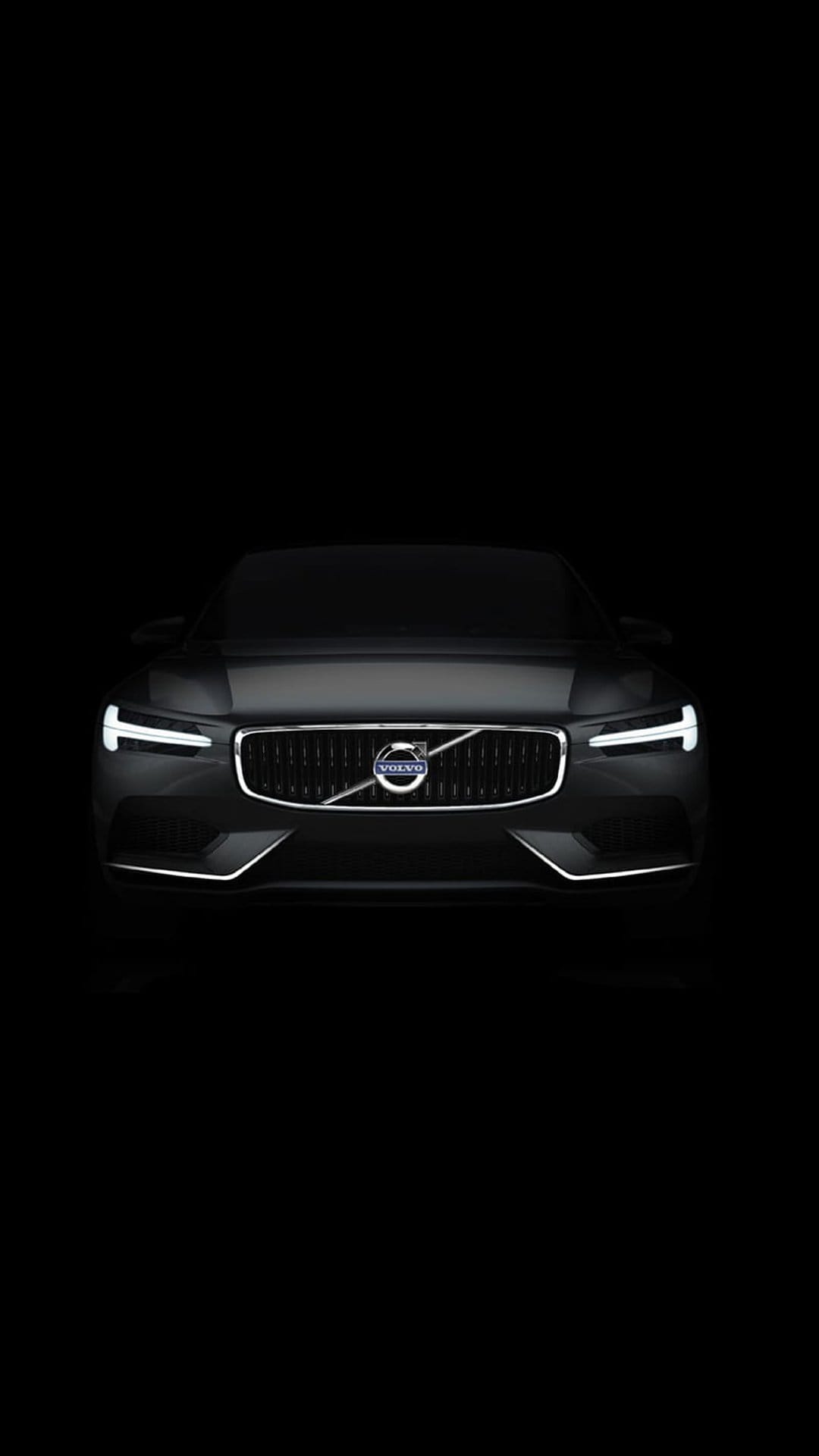 Volvo front grille with illuminated LED headlights and silver logo centered on a solid black background.