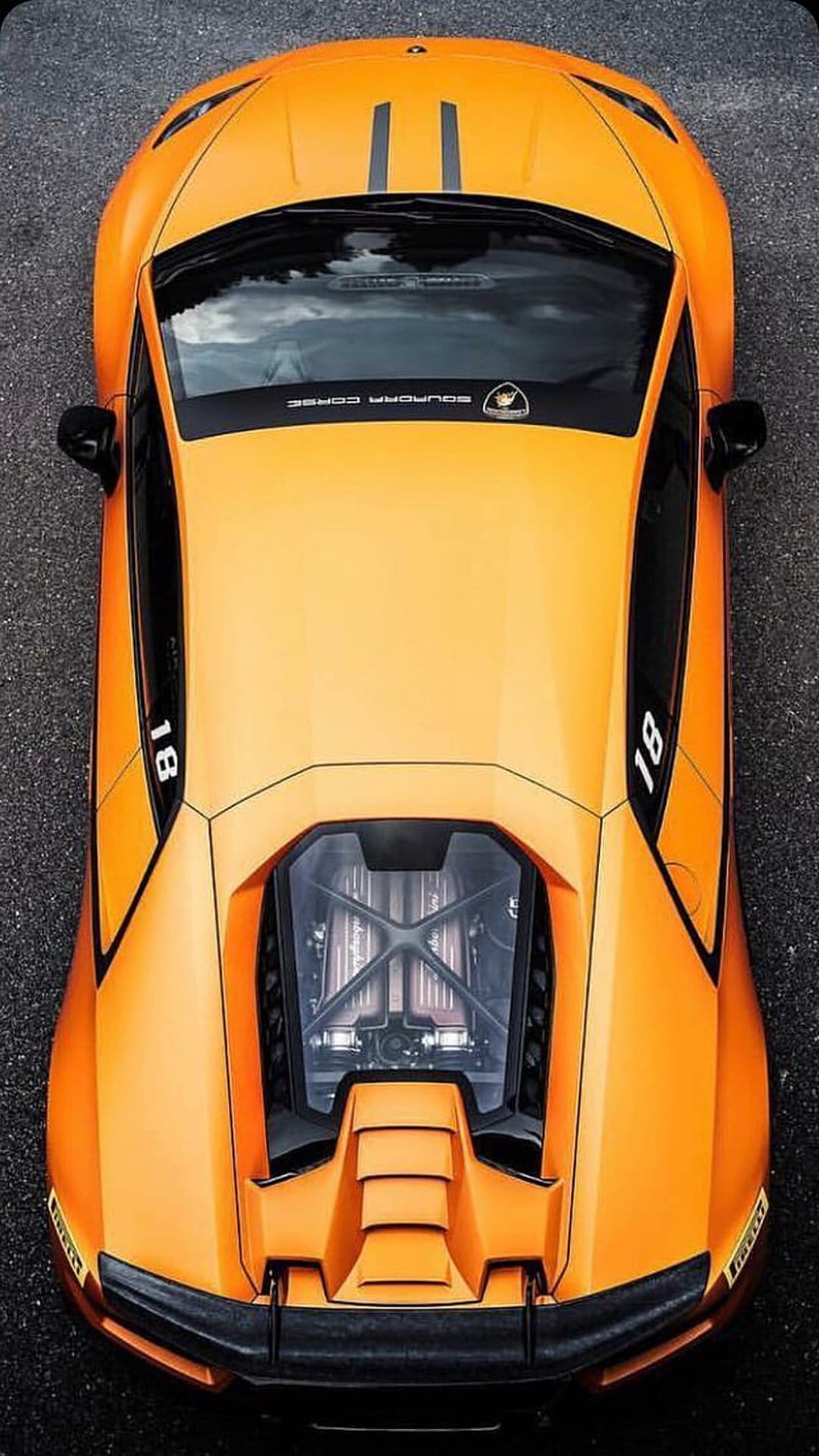Orange Lamborghini Huracan supercar from a top-down view featuring a visible engine bay and racing number 18.