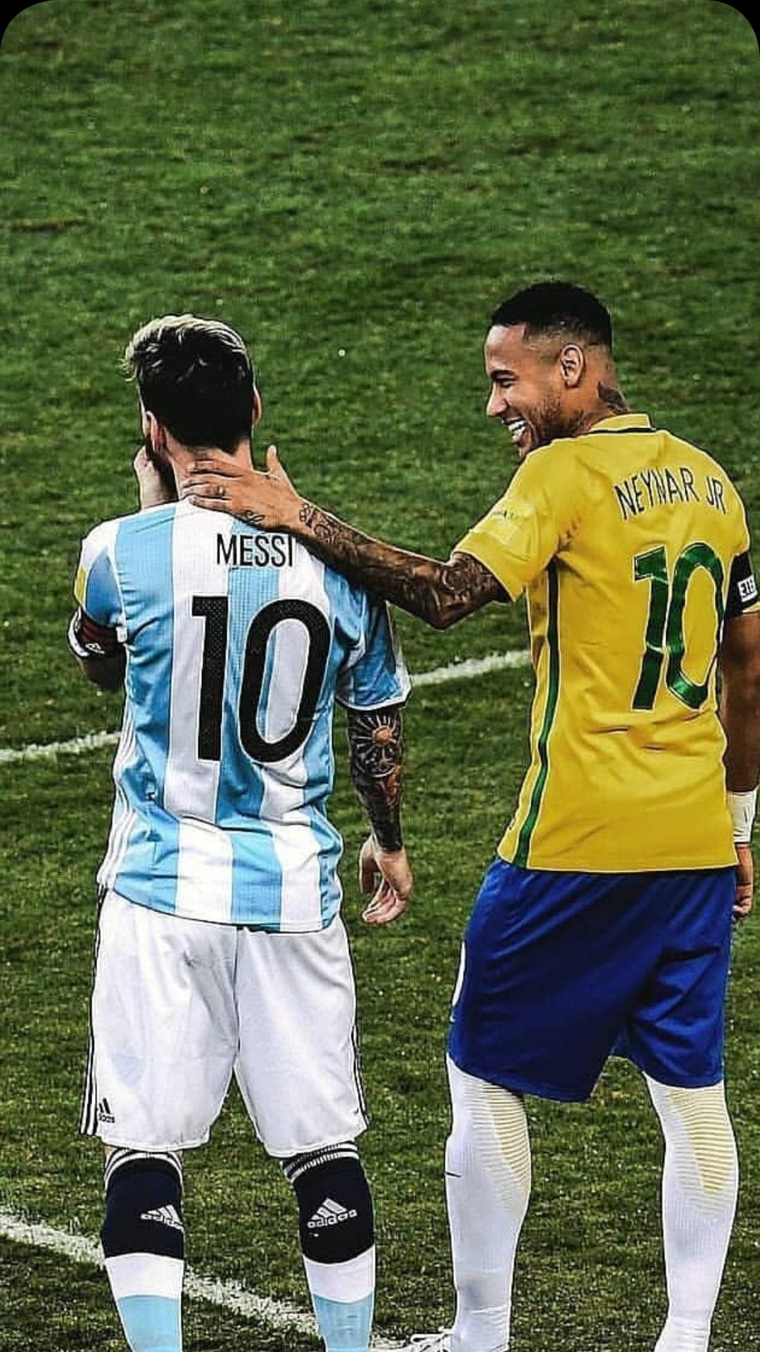 Lionel Messi in an Argentina jersey embraces Neymar Jr in a Brazil kit on a grass field during a football match.