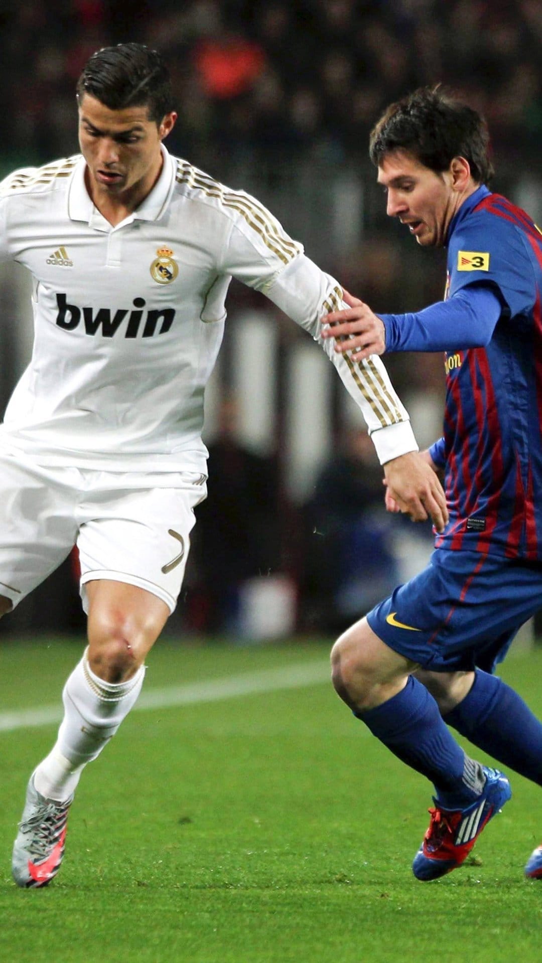 Cristiano Ronaldo and Lionel Messi face off in their respective team kits during an intense football match.