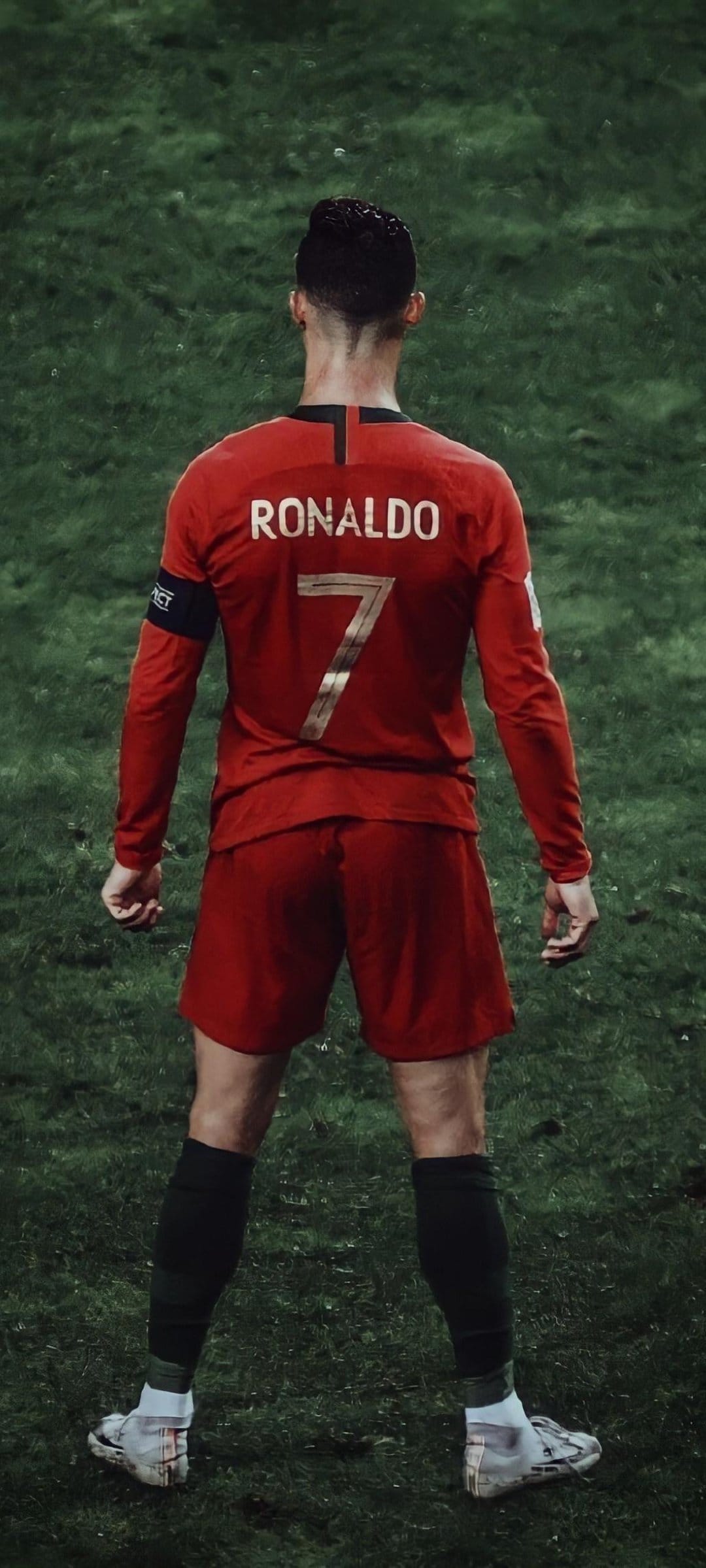 Cristiano Ronaldo seen from behind wearing a red Portugal jersey with number seven on a green football field.