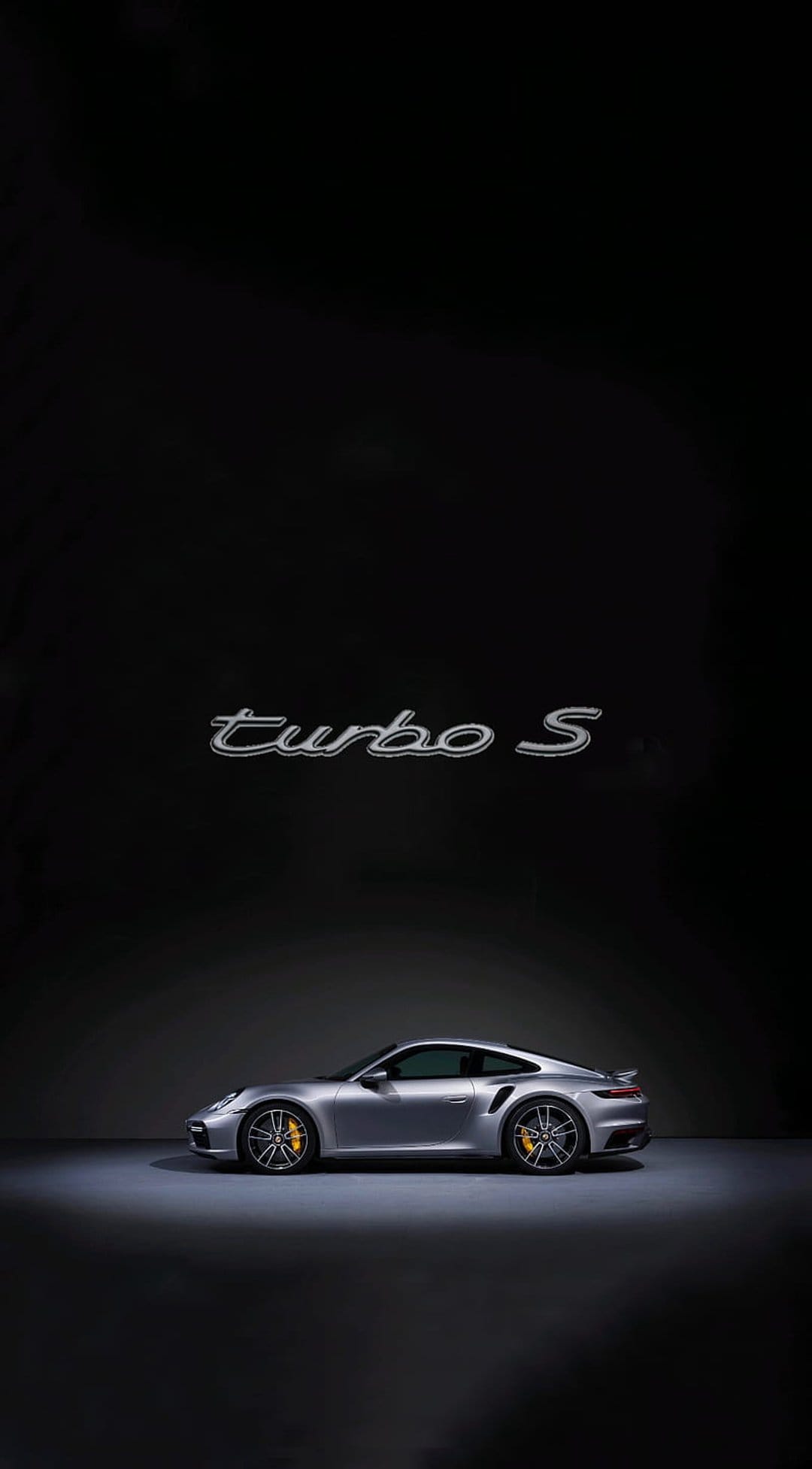 Silver Porsche 911 Turbo S supercar with yellow brake calipers and alloy wheels in a vertical profile view.