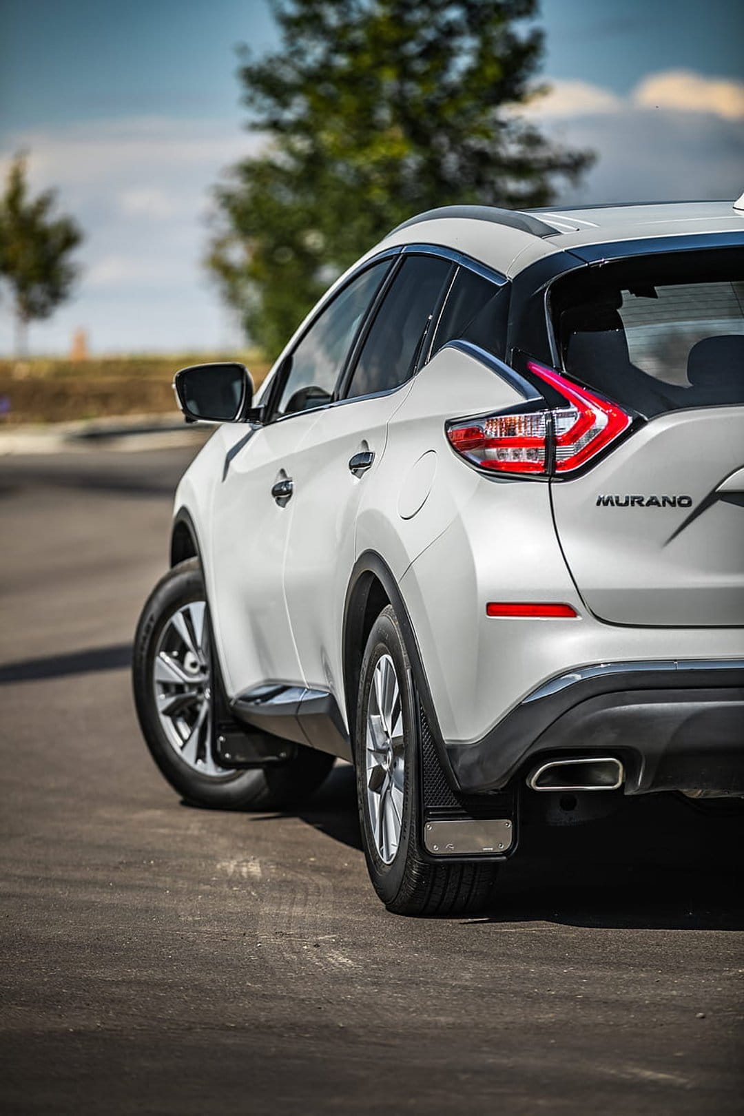Nissan Murano SUV rear quarter panel featuring a red taillight, chrome exhaust tips, and silver alloy wheels.