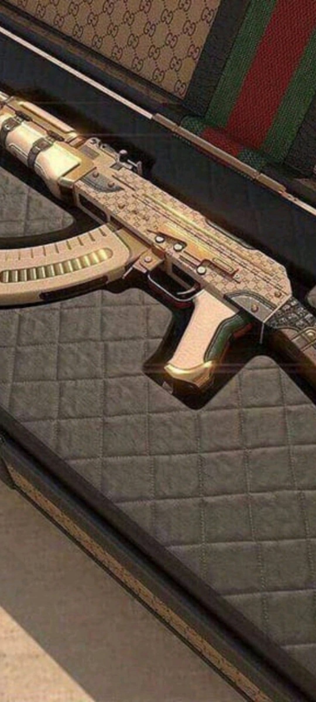 Gold-plated AK-47 rifle with GG monogram rests in a designer case featuring iconic green and red stripe patterns.