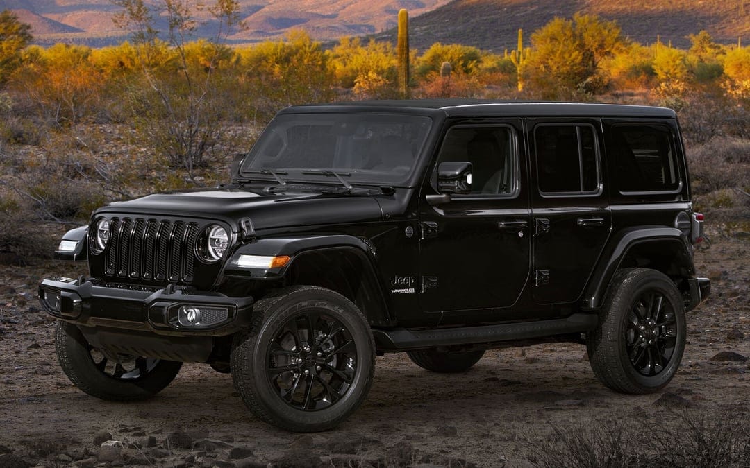 Black Jeep Wrangler Unlimited on rocky desert ground with Saguaro cacti and golden hour mountain views.