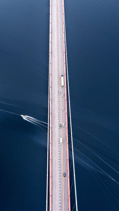 Aerial view, bridge, water, transportation, vehicles, speedboat, infrastructure, modern, engineering, travel, road, blue, high-angle shot, transit, structure, river, crossing, perspective, highway