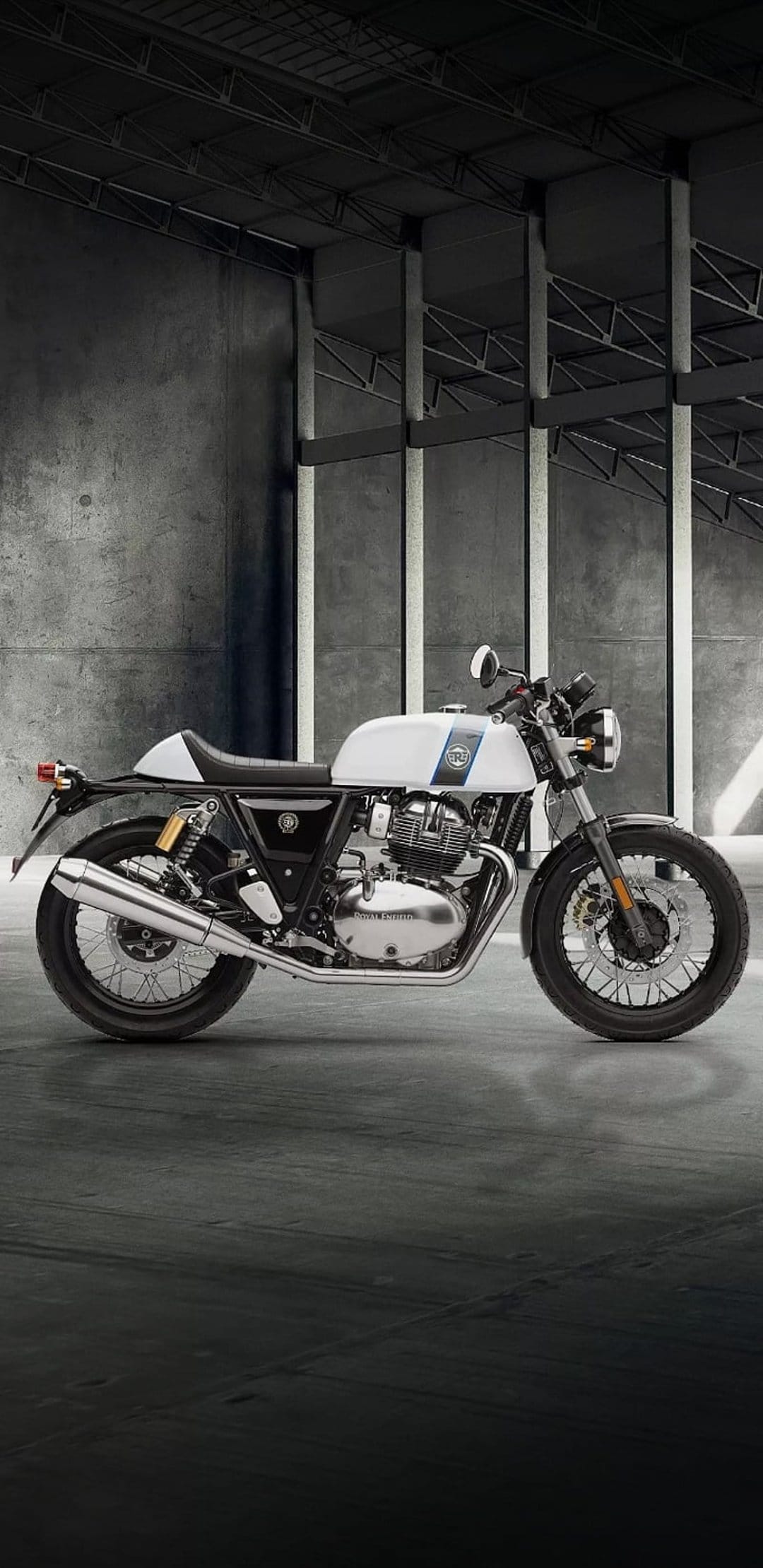Royal Enfield Interceptor 650 with blue stripes parked on concrete in a minimalist industrial garage.