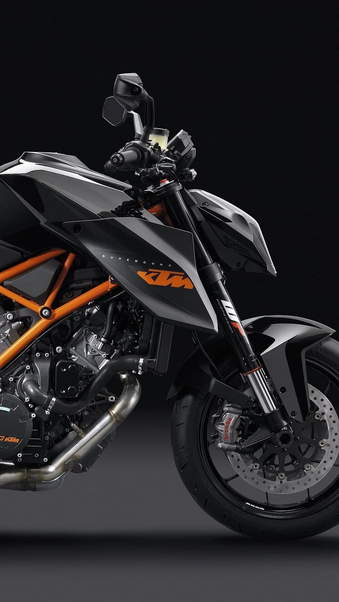 KTM 1290 Super Duke R motorcycle close-up featuring a black fairing, orange trellis frame, and V-twin engine detail.