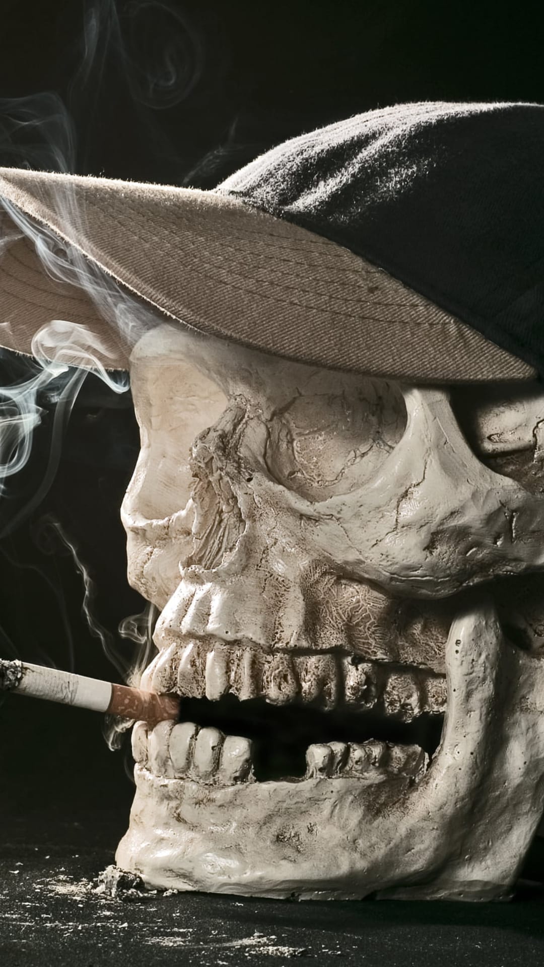 Skull in a peaked cap smoking a cigarette with thick vapor clouds drifting against a solid black background.