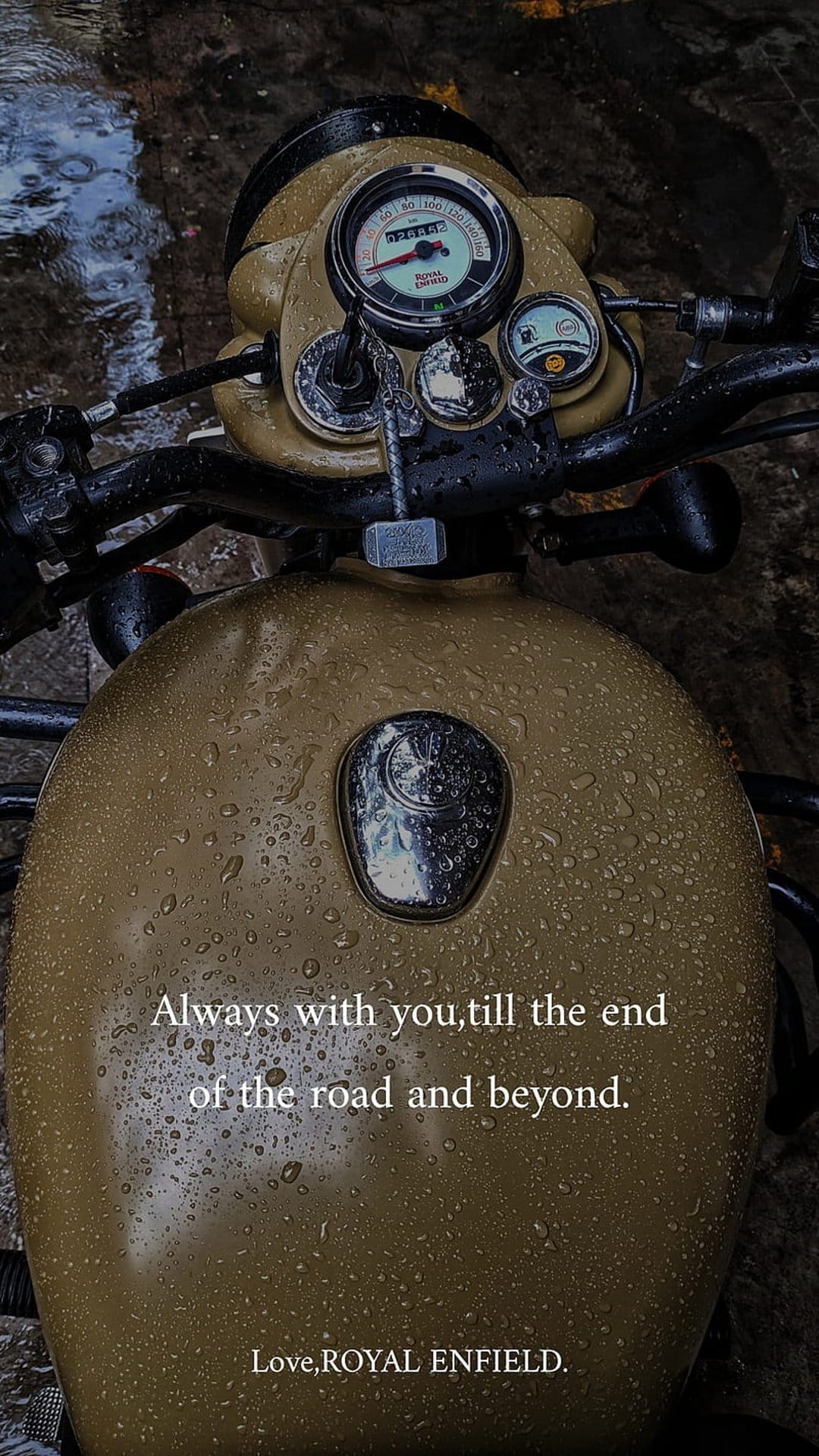 Tan Royal Enfield motorcycle tank covered in raindrops with white text about road companionship and loyalty.