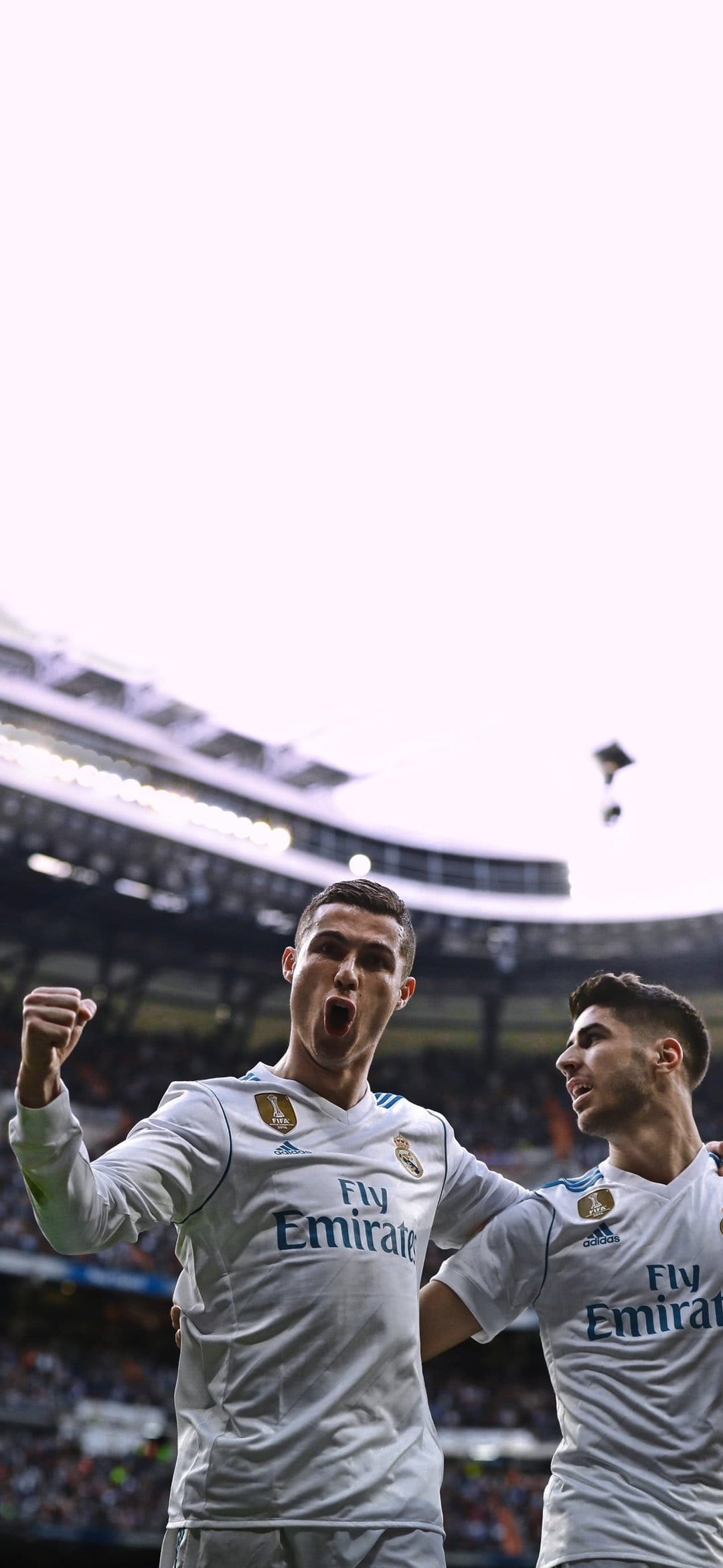 Cristiano Ronaldo raises a clenched fist in triumph wearing a white jersey beside teammate Marco Asensio.