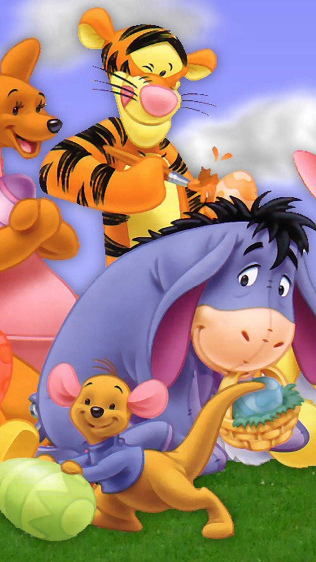 Tigger paints a shell as Roo pushes a large egg and Eeyore sits by a basket of blue eggs in the grass.