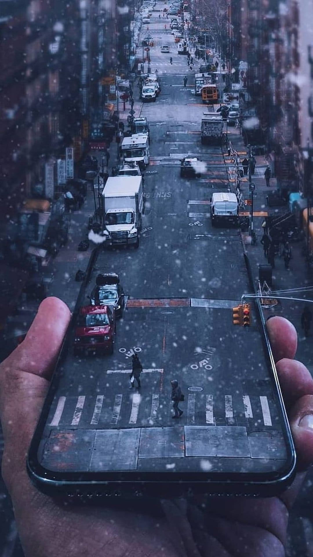Miniature snowy urban street with tiny pedestrians and cars displayed on a smartphone screen held by a hand.