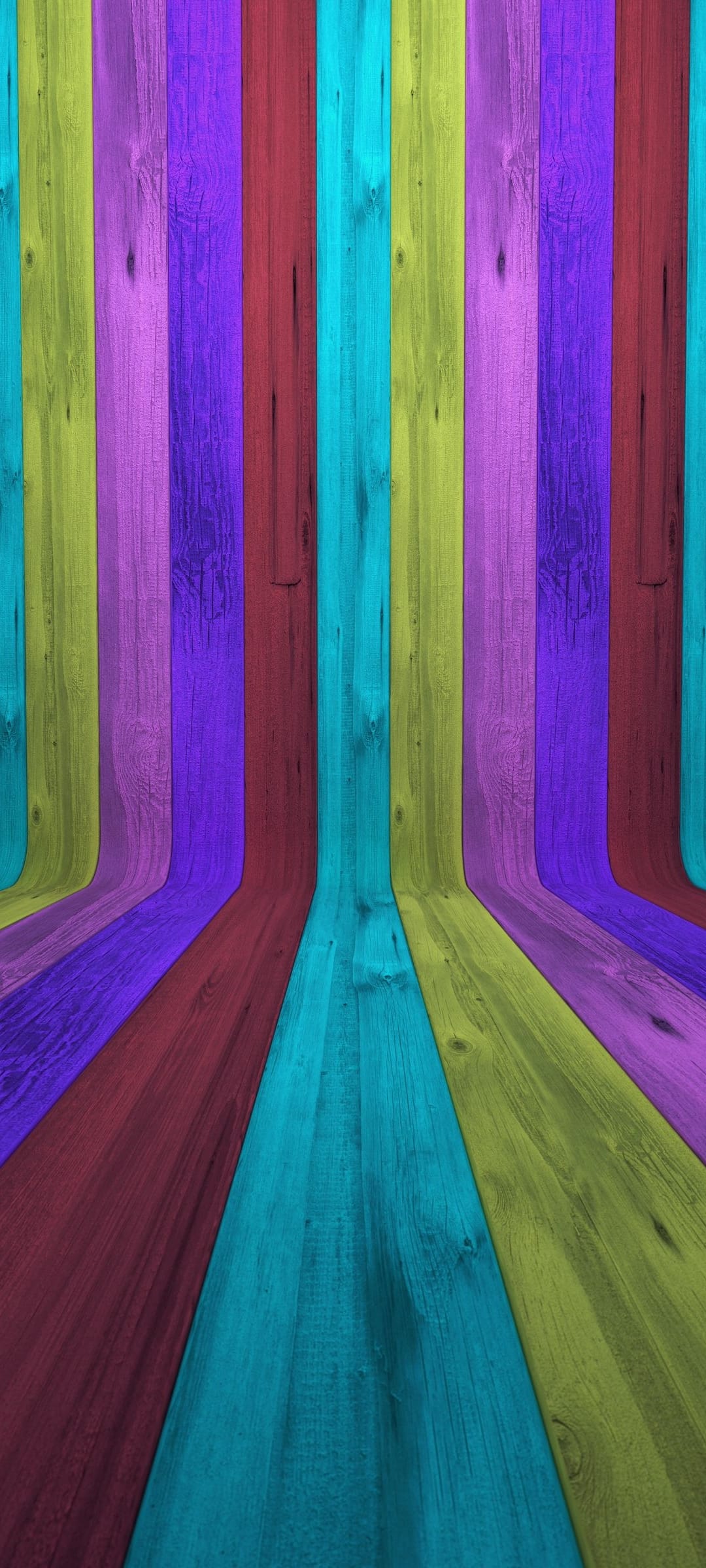 Vertical wooden planks in purple, red, and cyan curve inward to form a deep, colorful architectural tunnel.