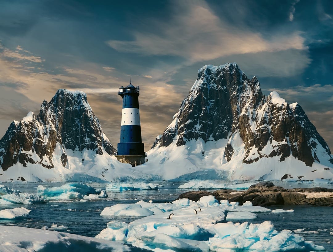 Blue and white lighthouse standing on an icy shore surrounded by snow-capped mountains and a group of penguins.