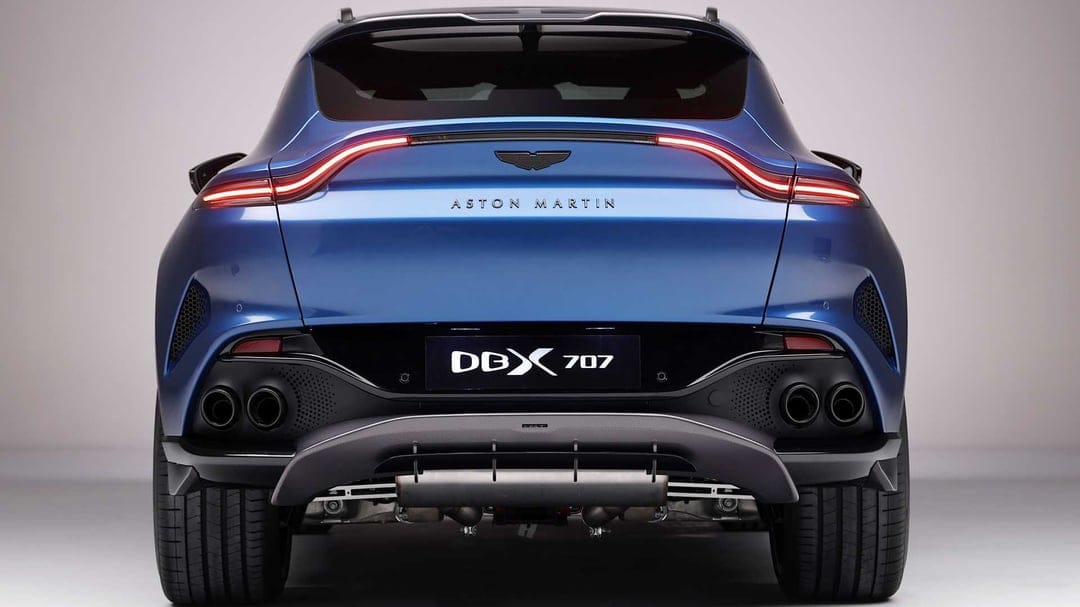 Rear view of a blue Aston Martin DBX 707 SUV with quad exhausts, LED taillights, and carbon fiber diffuser.