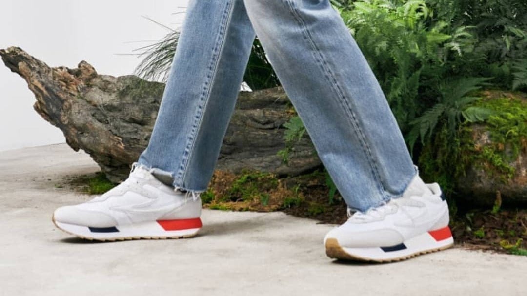 White Fila sneakers with red and blue sole accents shown in a vertical composition for mobile backdrops.