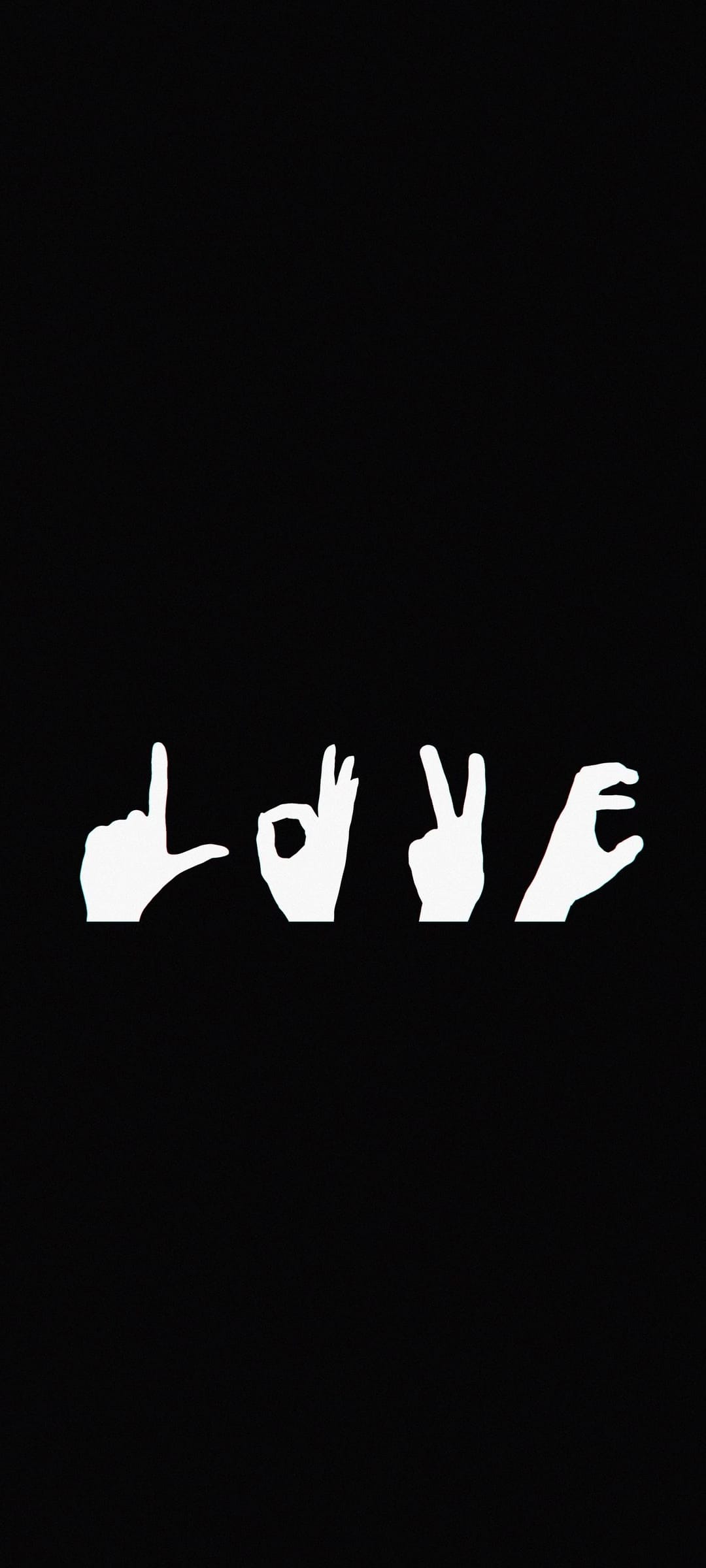 White hands positioned to spell the word love in American Sign Language against a dark, high-contrast backdrop.