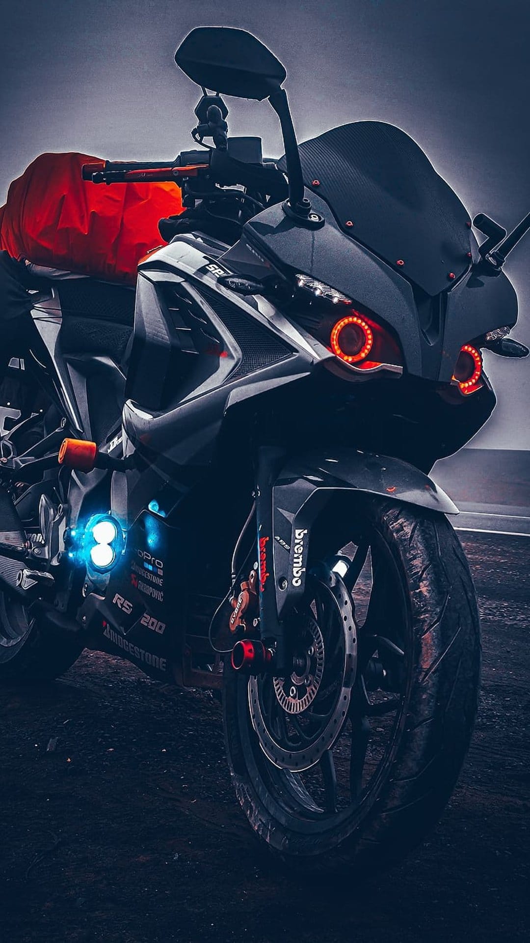 Sportbike with glowing red halo rings and blue LED lights shows Brembo hardware against a dark background.