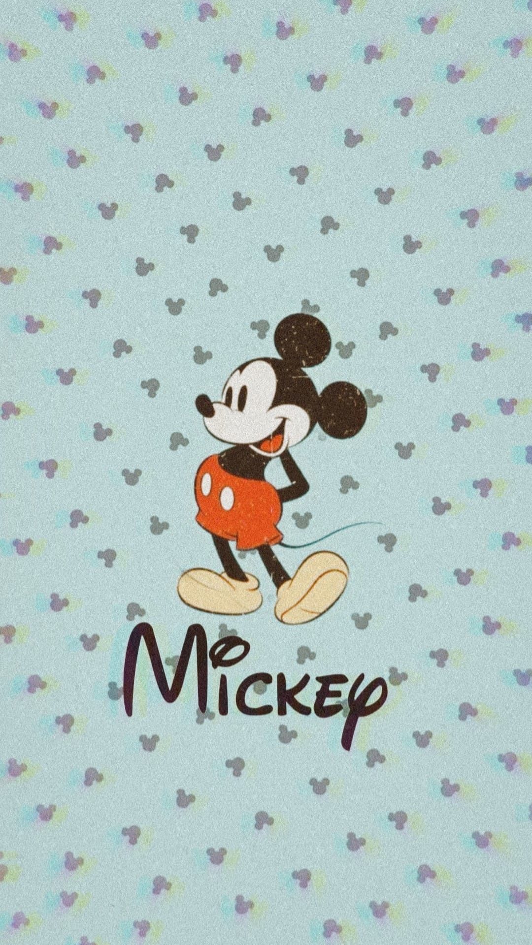 Mickey Mouse in red shorts and yellow shoes stands against a blue textured pattern of small mouse head icons.