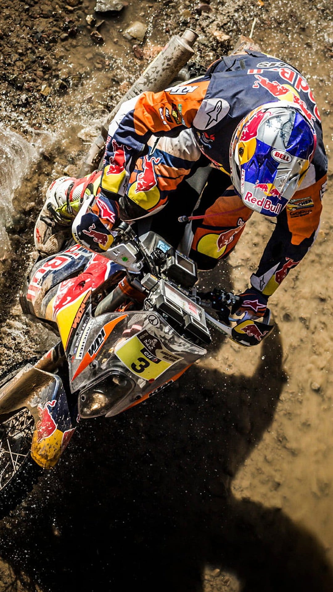 Motocross rider in full racing gear leans into a muddy turn with water splashing from the bike's rear tire.