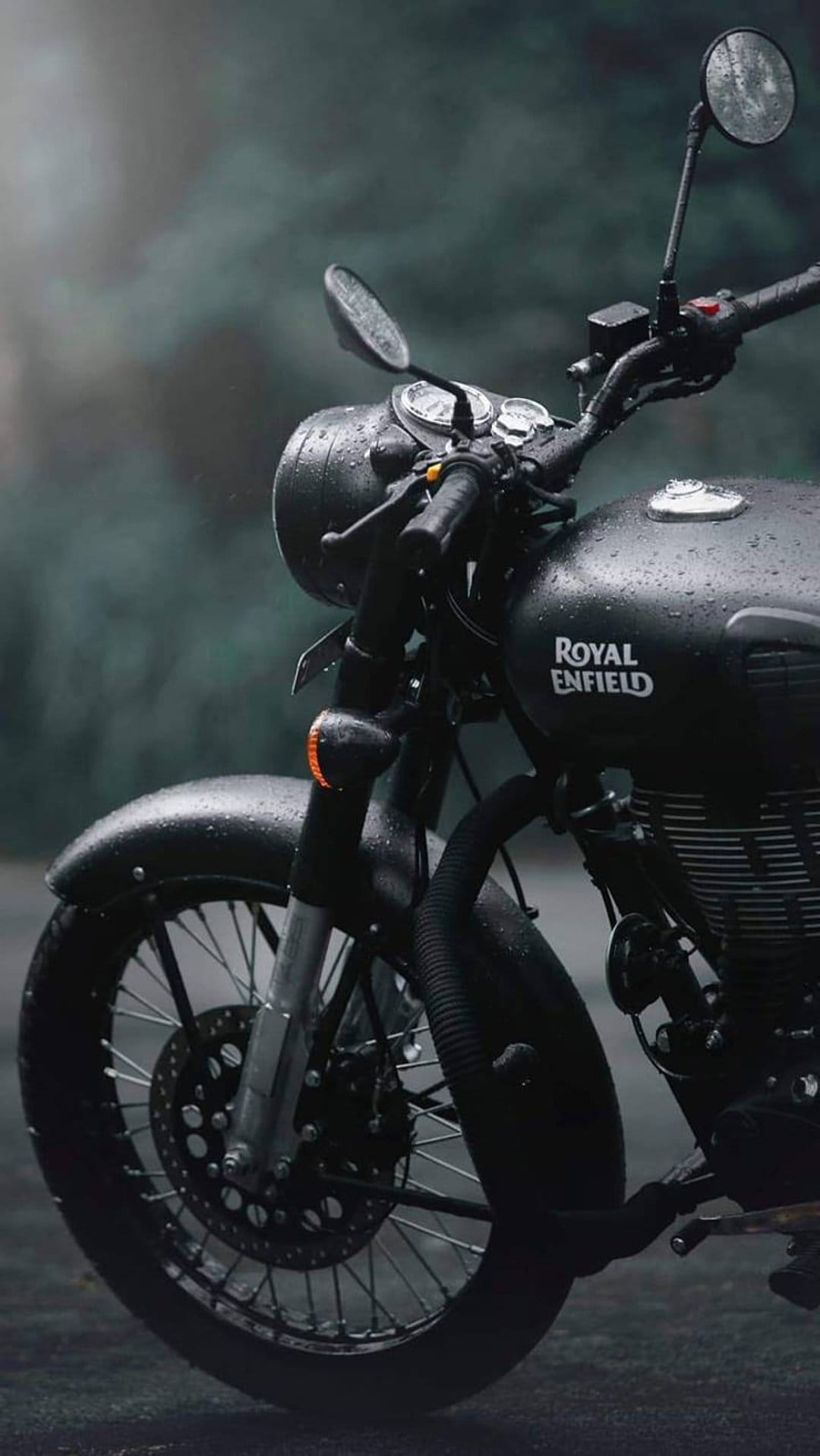 Black Royal Enfield motorcycle with wet chrome surfaces and raindrops on its fender parked on a dark rainy street.