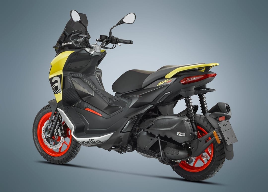 Rear view of a yellow and black Aprilia SR GT scooter with bright red wheels against a gray background.
