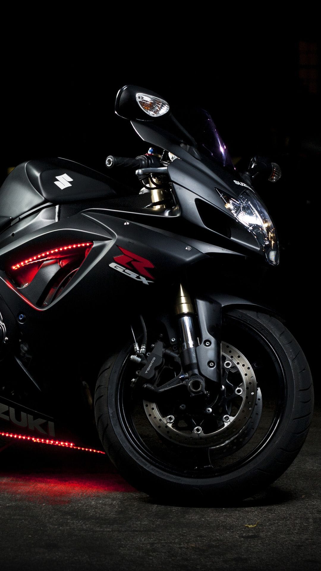 Suzuki GSX motorcycle featuring red LED lighting on the fairing and front wheel against a dark backdrop.