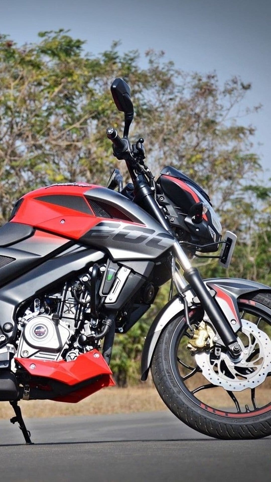 Red and gray sportbike motorcycle features a detailed engine and front disc brake on an asphalt road.