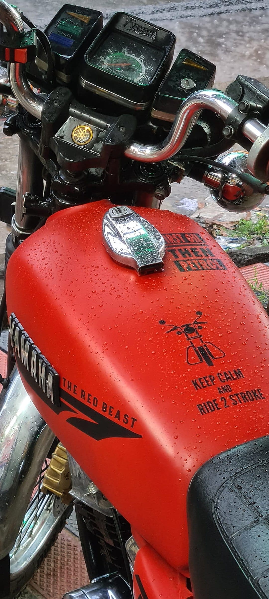 Red Yamaha motorcycle fuel tank with raindrops, chrome cap, and The Red Beast custom graphic lettering.