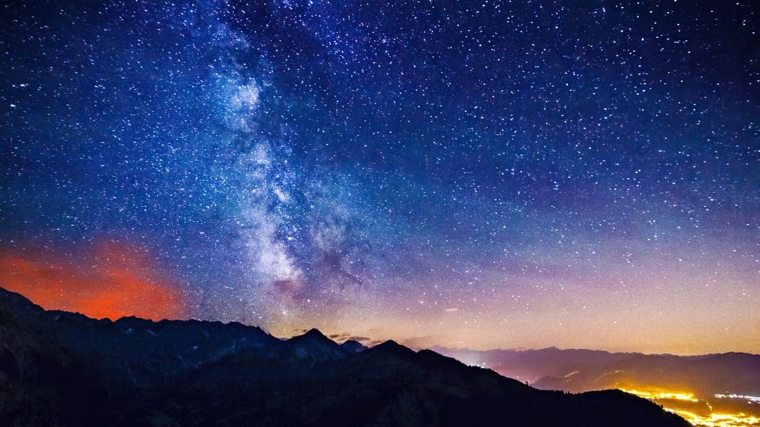 Mountain landscape digital illustration featuring sharp dark silhouettes under a starry night sky with nebulae.