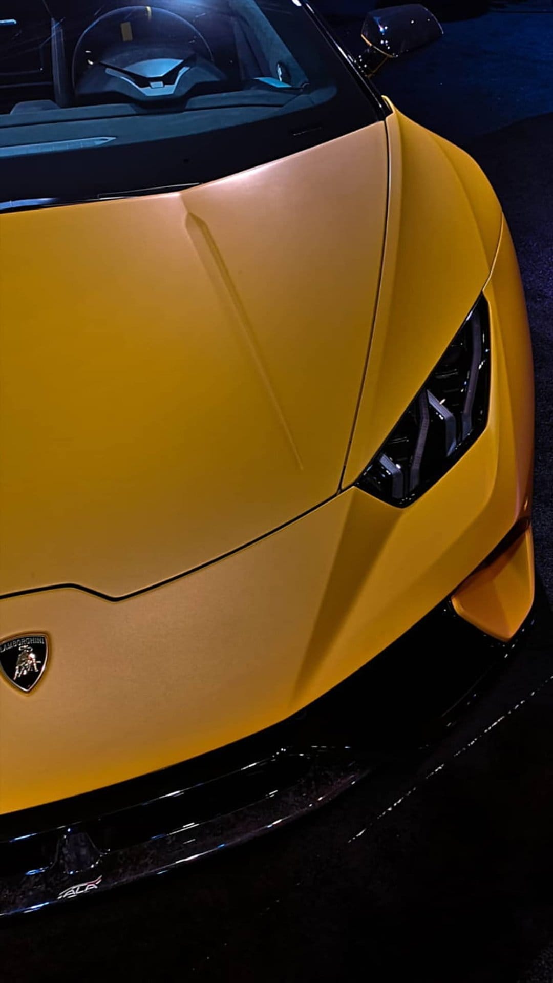 Yellow Lamborghini hood with sharp aerodynamic lines, a central bull crest, and modern LED headlight details.