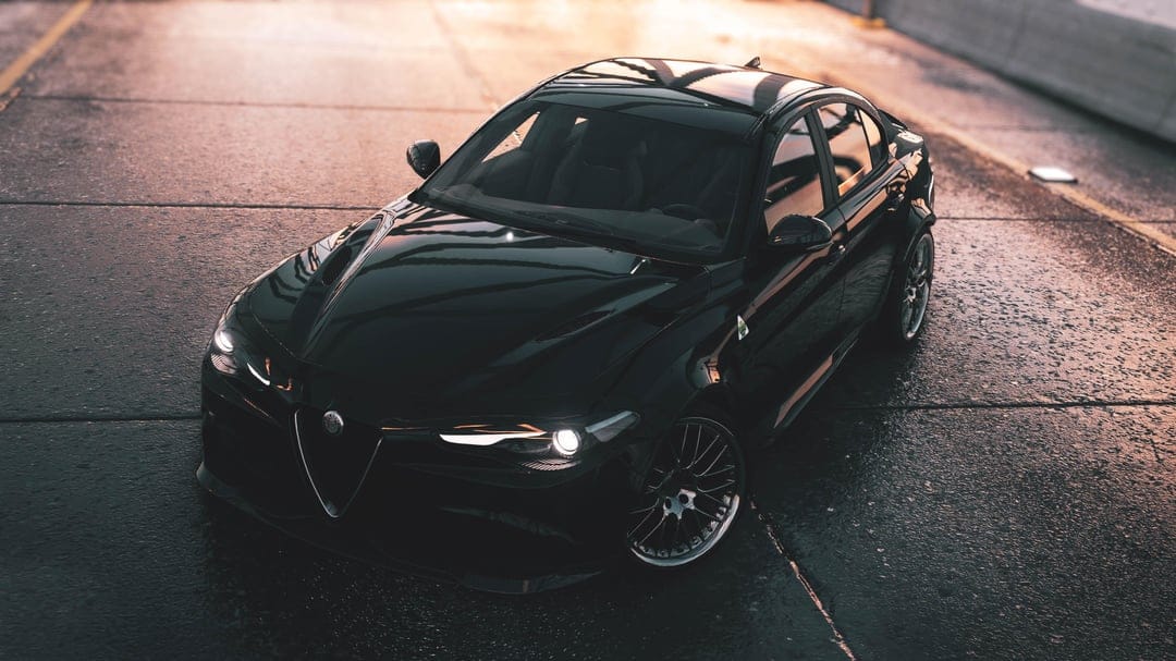 Black Alfa Romeo Giulia sport sedan on wet asphalt reflecting golden sunset light in a cinematic scene.