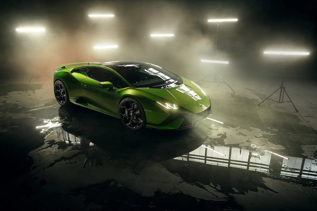 Green Lamborghini supercar in a dark foggy studio with light bars and reflections on a wet floor.