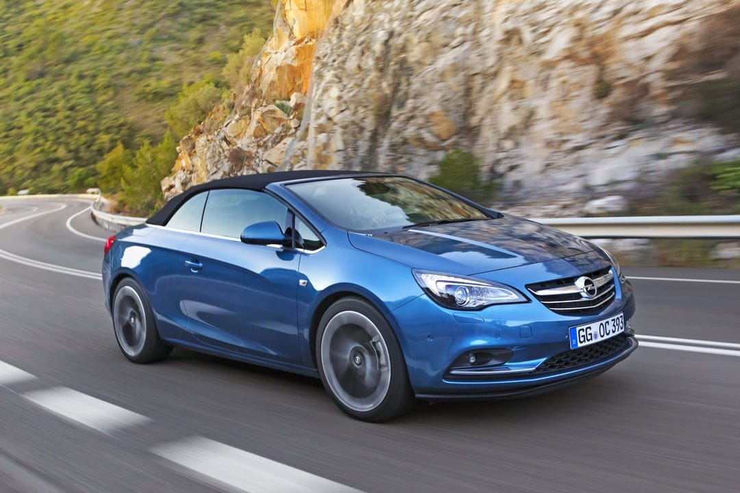 Blue convertible car driving fast on a winding road next to a rocky cliffside with dynamic motion blur effects.