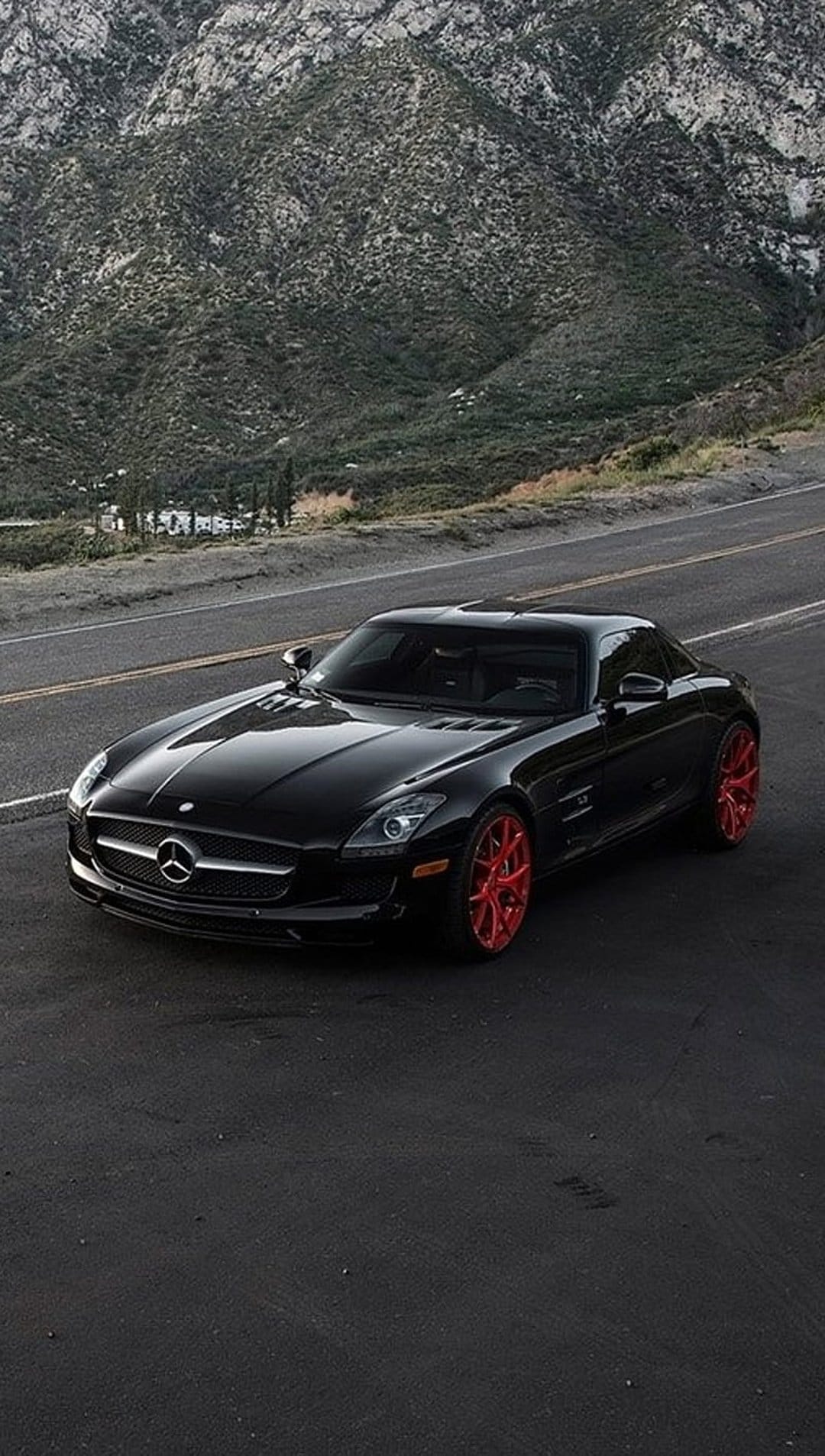 Mercedes SLS AMG with red wheels parked diagonally on a mountain road, providing a high-contrast mobile background.