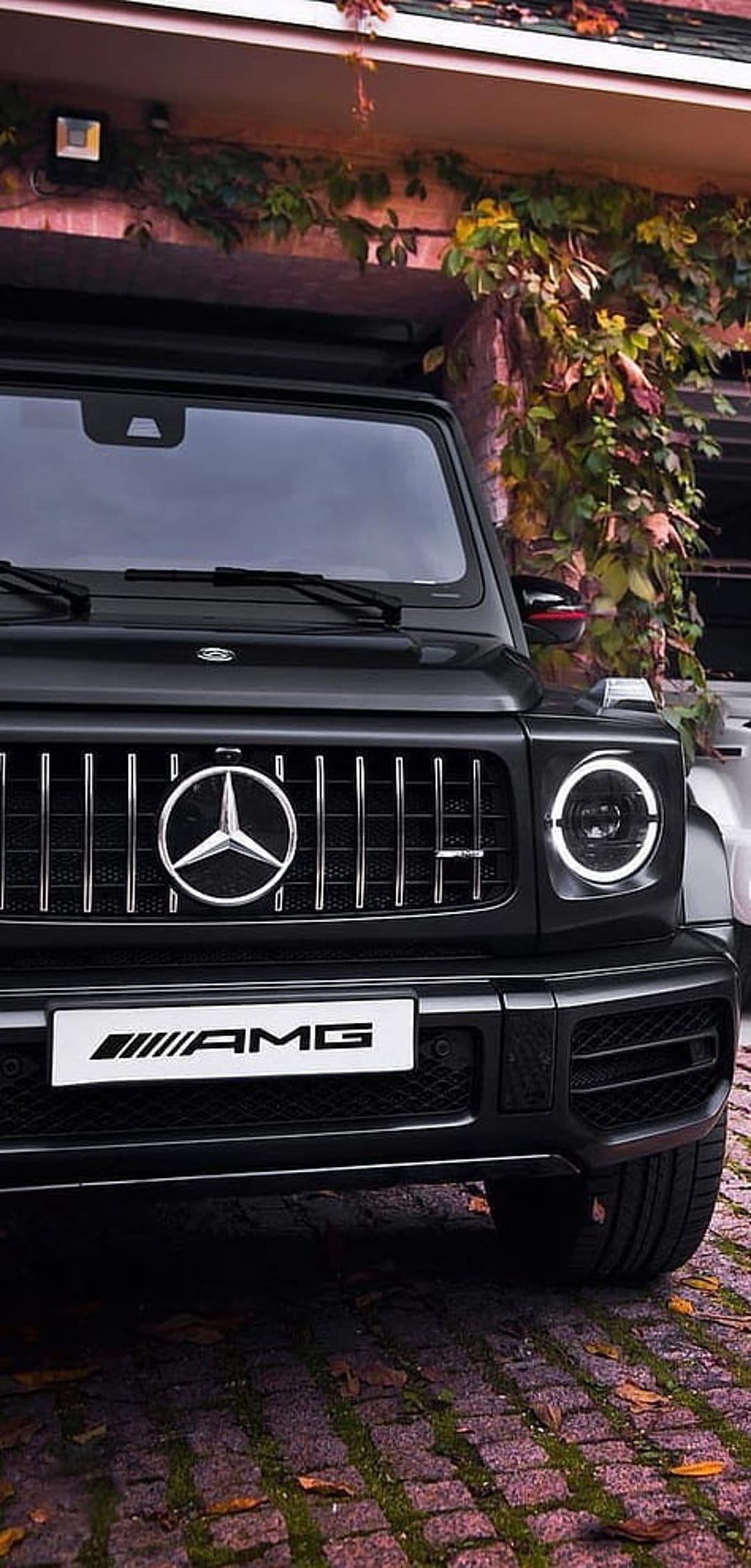 Mercedes-AMG G 63 front grille and round LED headlights featuring a chrome star emblem on a black SUV.