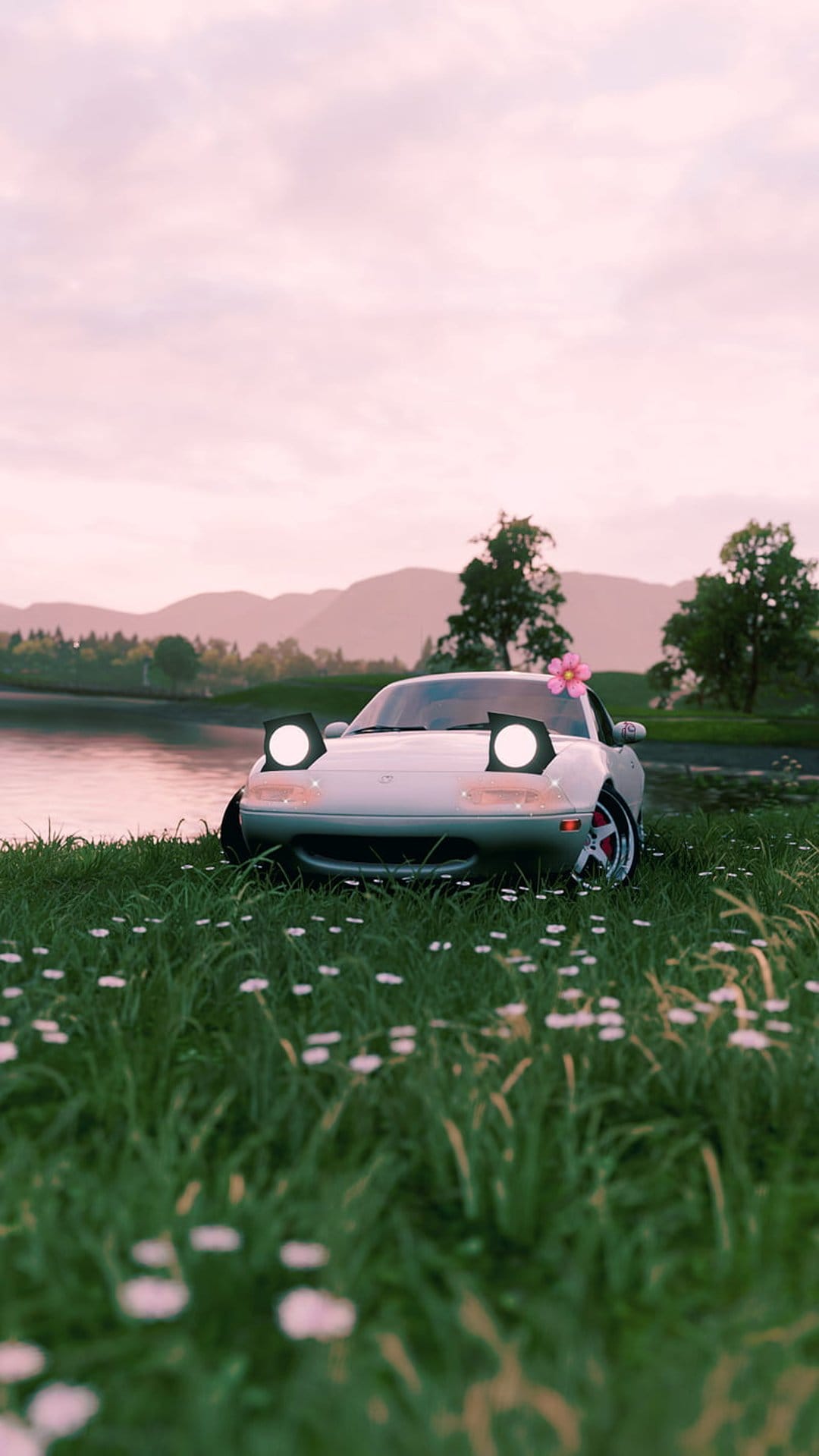 White car with pop-up headlights and a pink flower on its hood sits in a field of wildflowers by a misty lake.