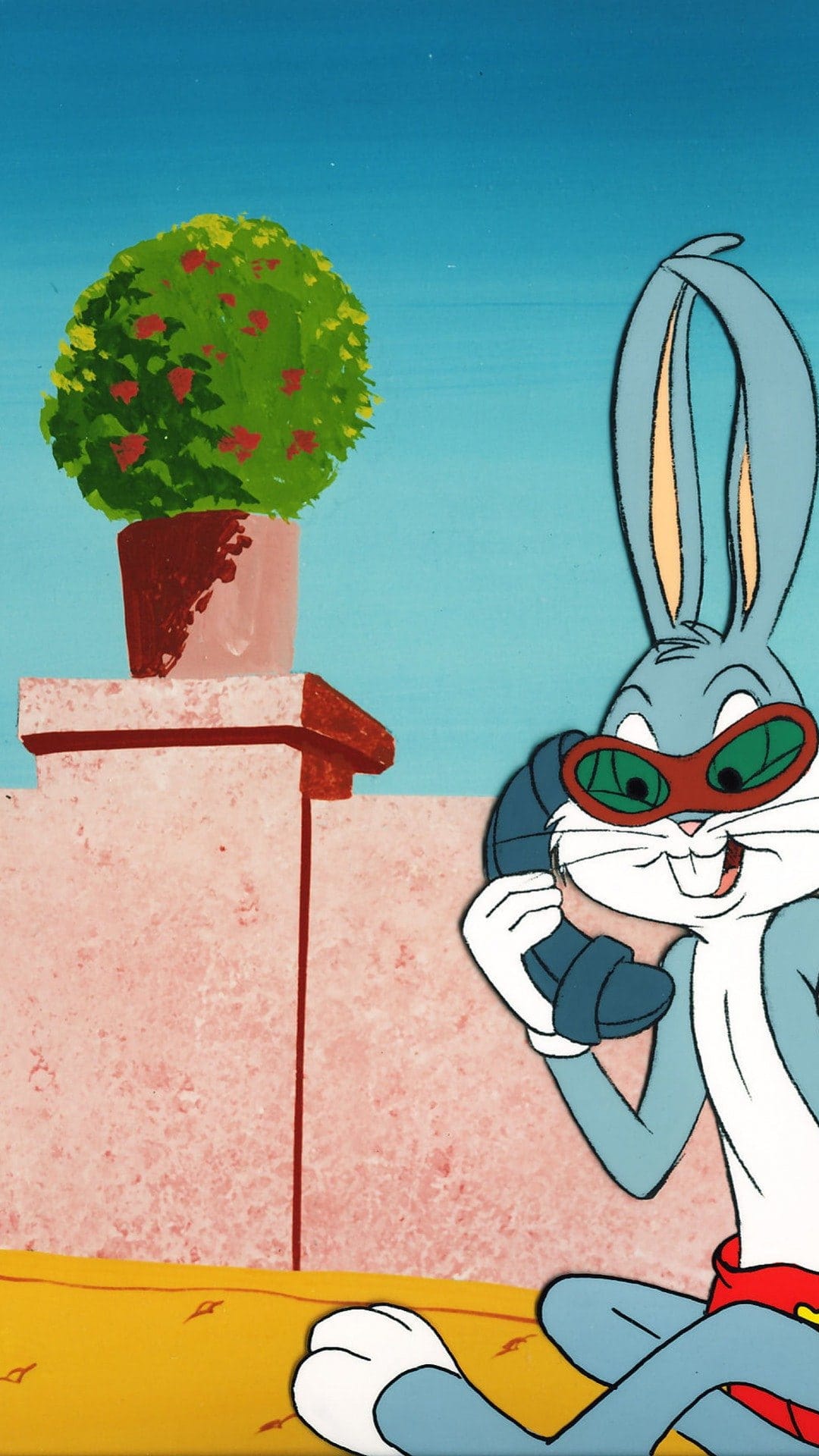 Bugs Bunny wears red goggles and holds a retro phone, standing beside a potted plant against a blue sky.