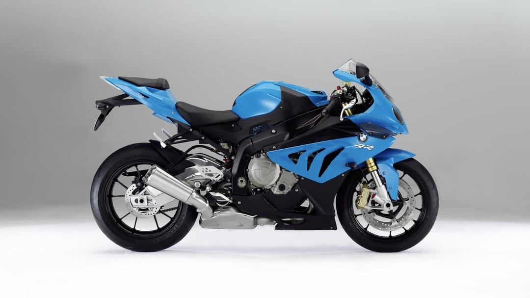 Blue BMW S1000RR sportbike with gold forks and silver exhaust in a side-profile studio shot on a grey background.