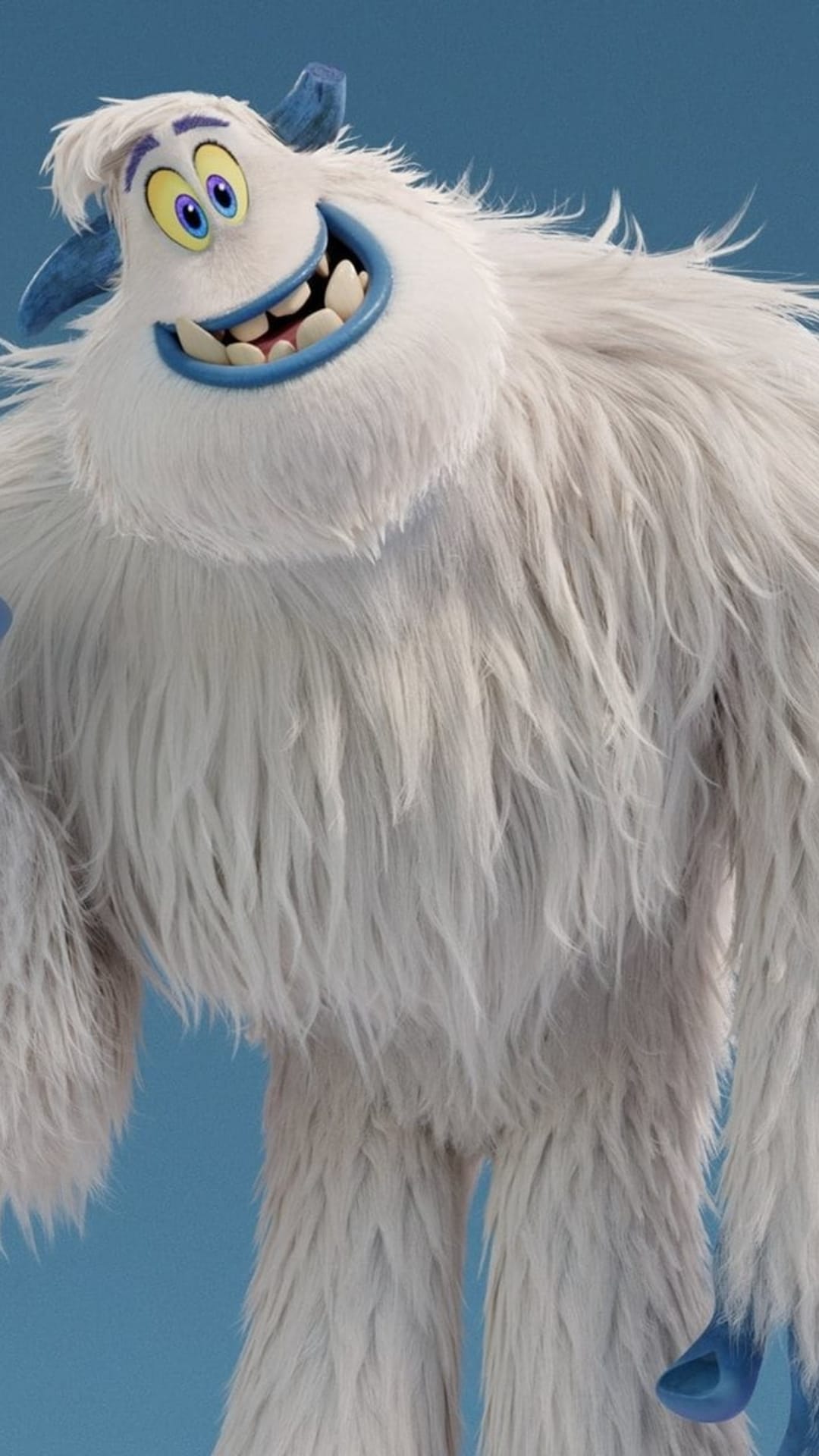 Migo the yeti smiles joyfully, showing blue gums and yellow eyes with purple irises against a light blue background.