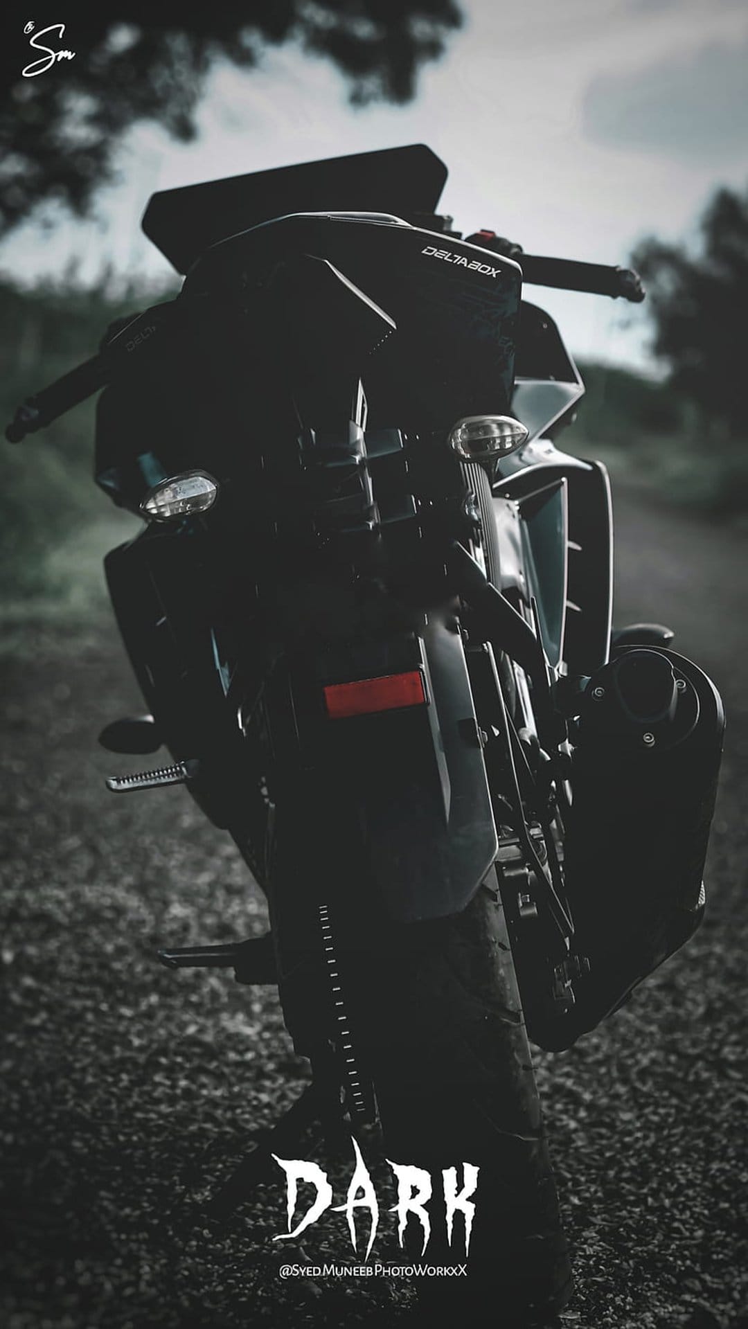 Matte black sportbike tail section with visible exhaust and stylized text under low atmospheric night lighting.