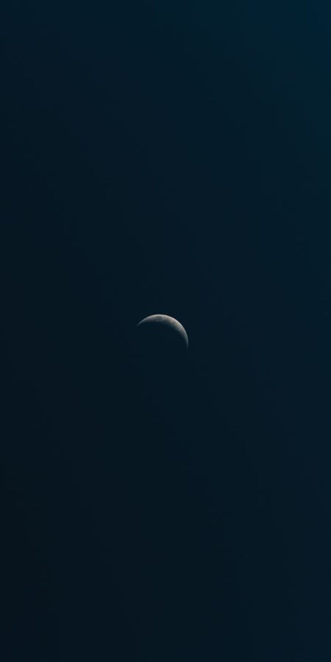 Slender crescent moon glowing softly against a dark blue gradient sky with subtle atmospheric haze and depth.