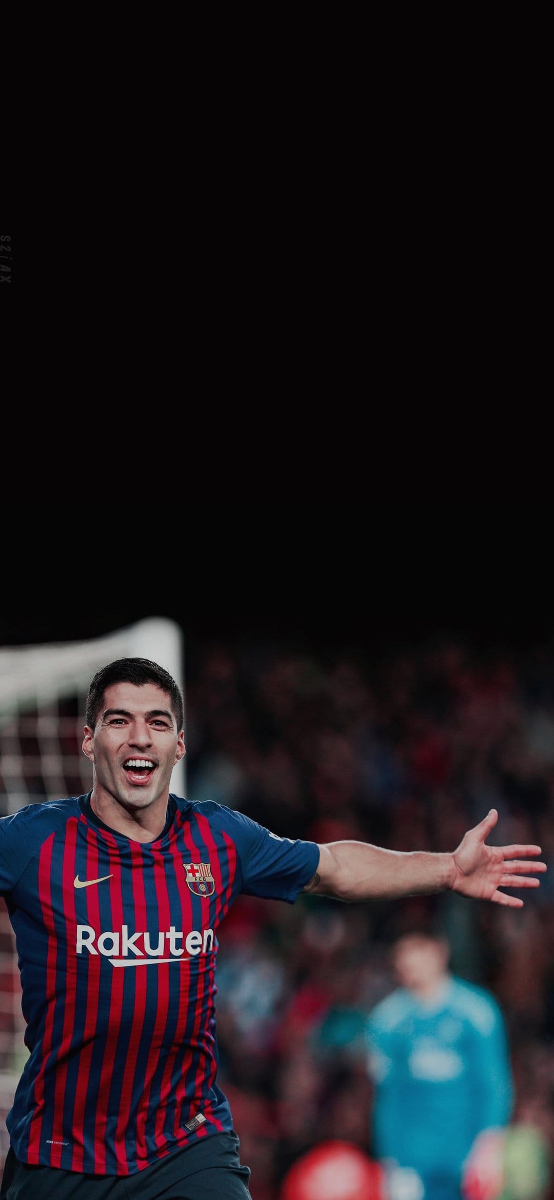 Luis Suarez shouts with arms outstretched while wearing a striped Barcelona jersey in a blurred football stadium.